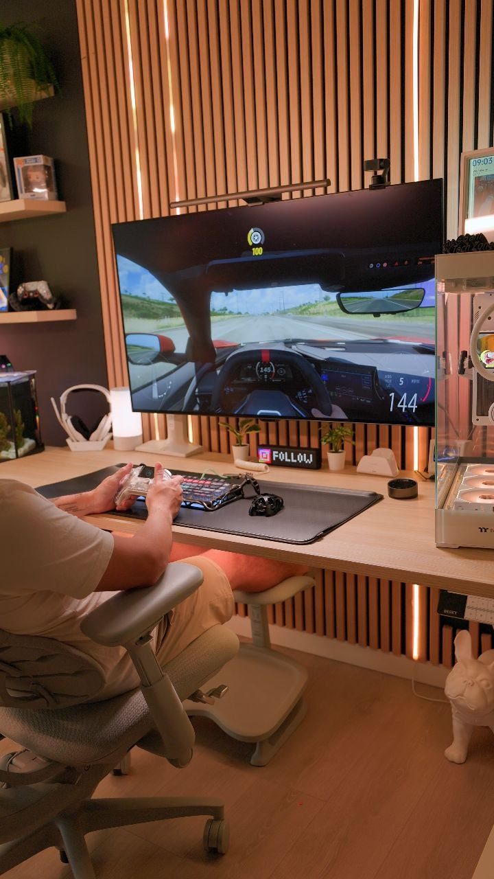 Man playing a racing game at a desk with wooden slat wall lighting