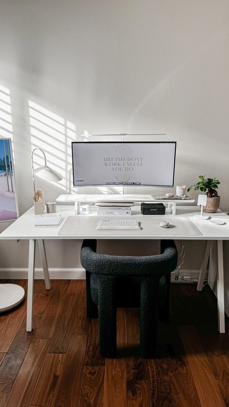 Minimalist white home office desk with monitor, keyboard, and black textured chair.