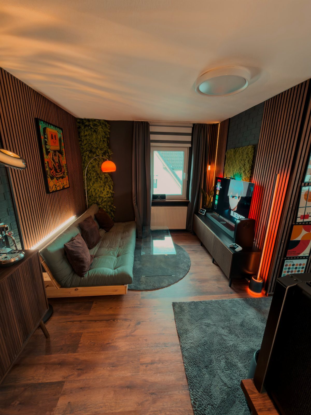 Home cinema room with teal sofa, ambient orange lighting, and large television screen.