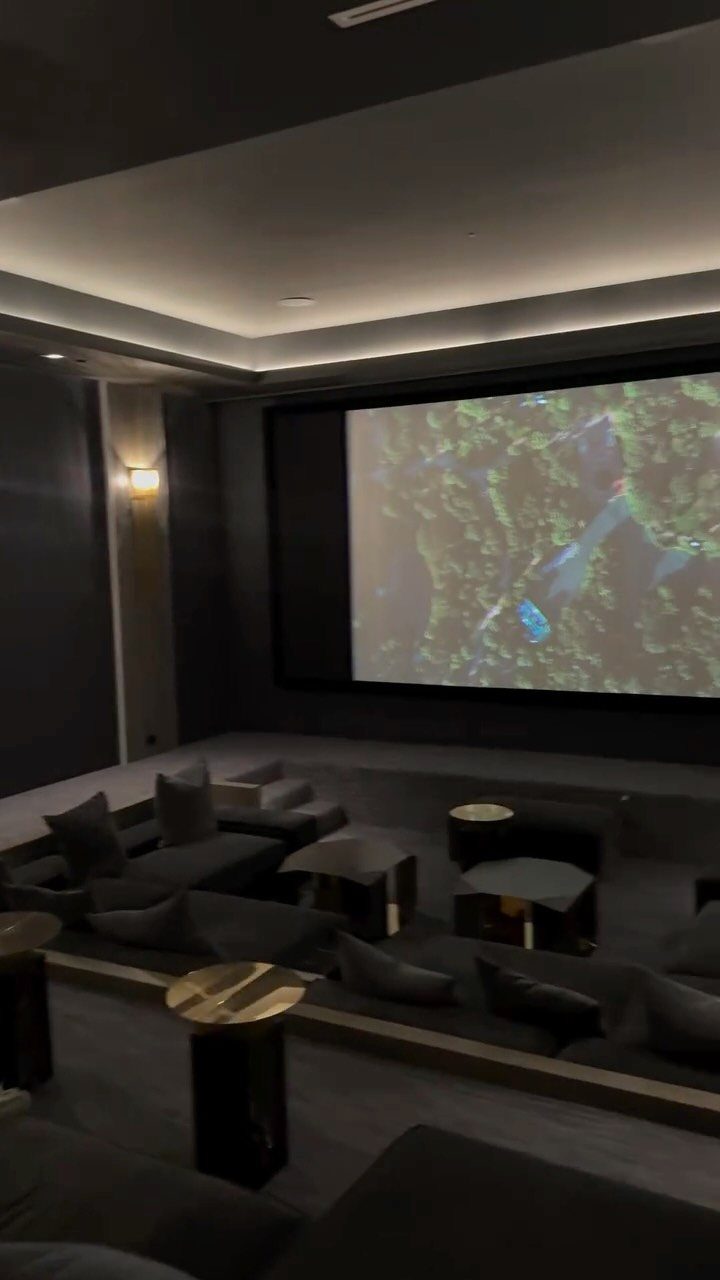 Home cinema room with large projection screen and rows of grey plush seating.