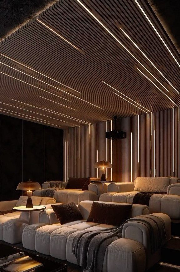 Modern home movie room with linear LED lighting and plush grey seating.