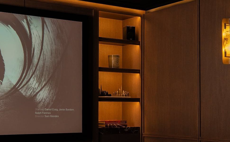 Home cinema room with a large projection screen and warm wooden shelving units.