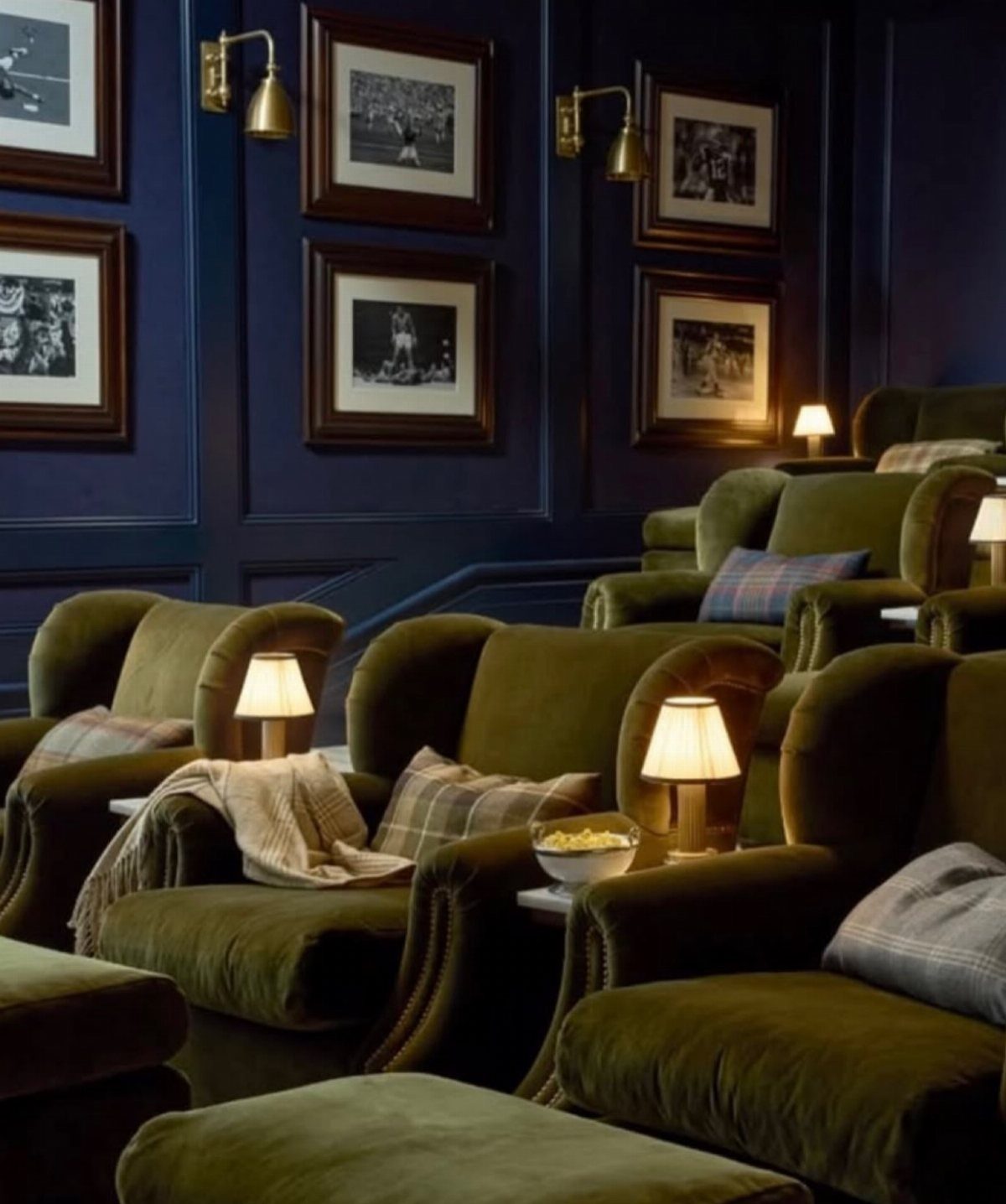 Luxury home cinema with olive green velvet chairs and dark blue paneled walls.