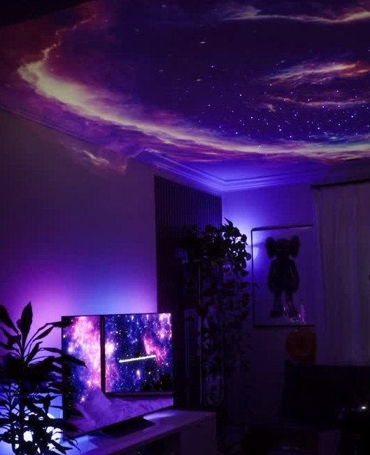 Galaxy nebula ceiling and matching television screen in a purple lit dark room