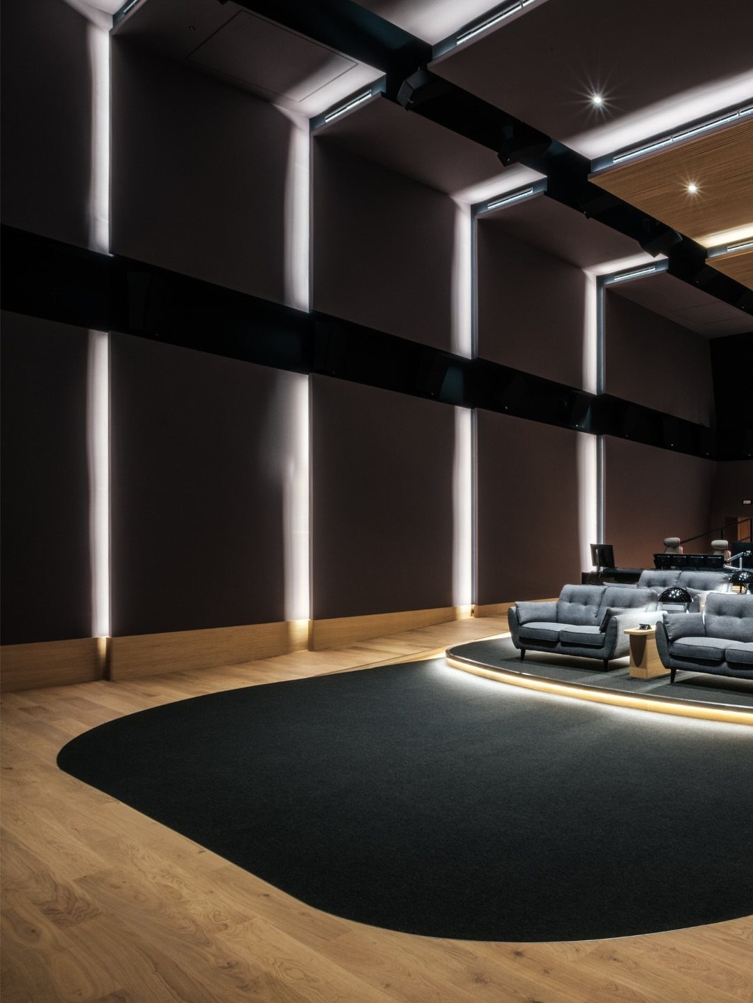Modern home cinema room with dark walls, vertical lighting, and grey lounge chairs.
