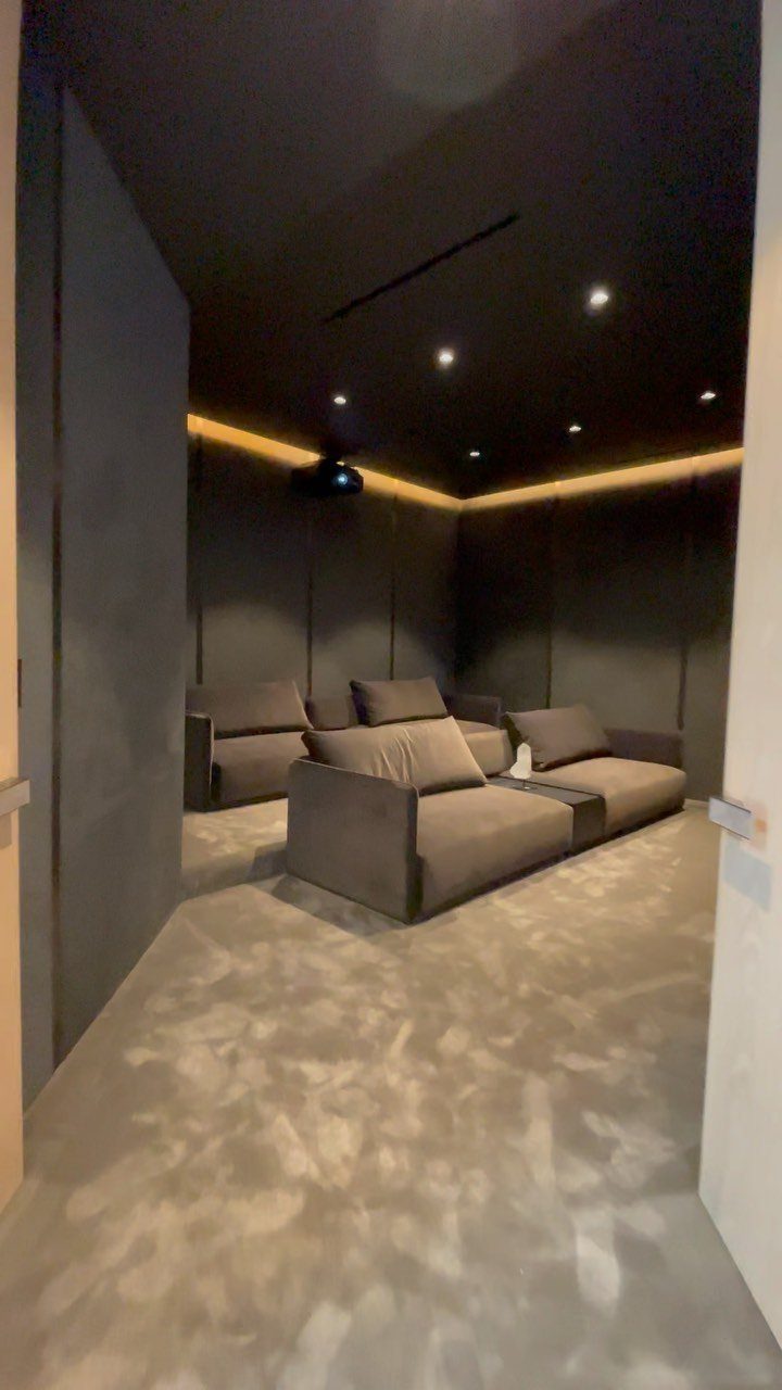 Dark home cinema room with grey plush seating and a grey carpet.