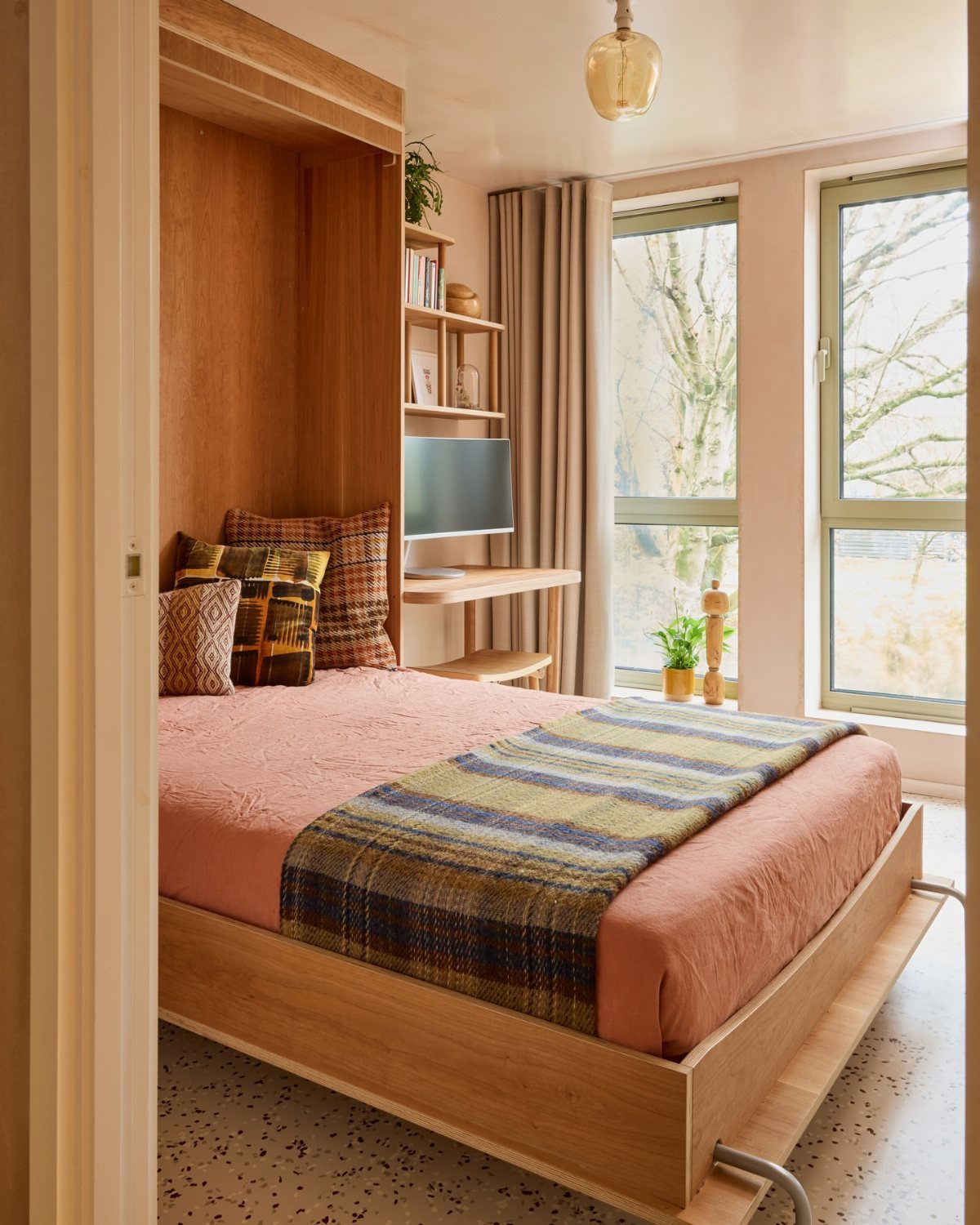 Murphy bed with pink bedding pulled down in a home office setting