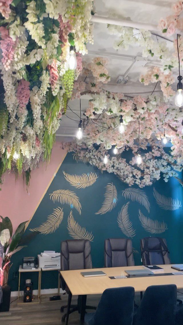 Office interior with floral ceiling, teal wall with gold leaves, and wooden desk.