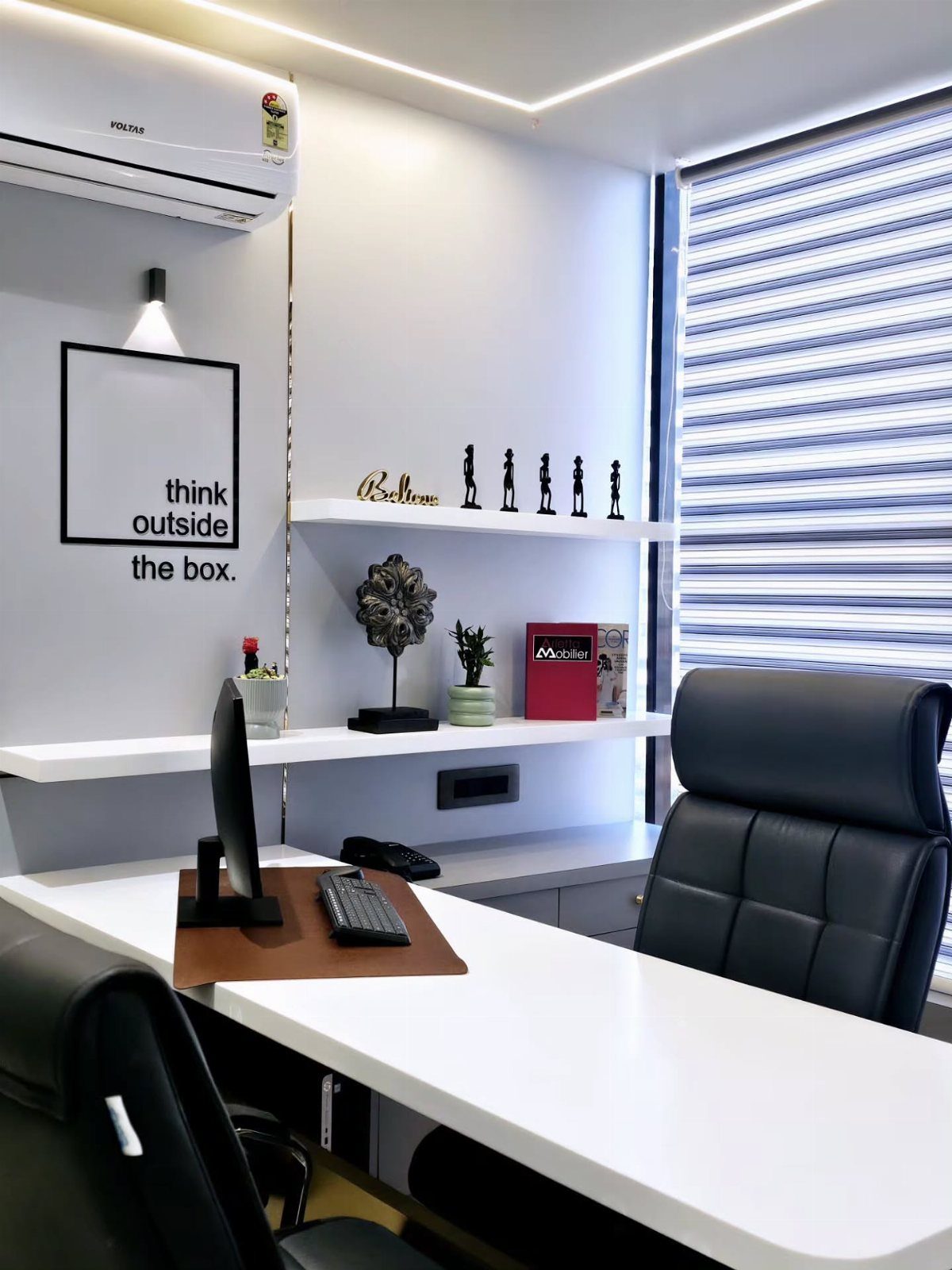 White office desk with computer and leather chair next to a window