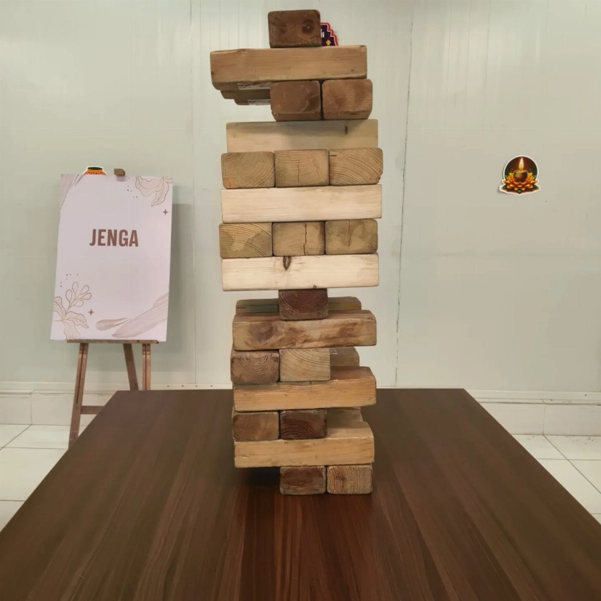 Giant wooden Jenga block tower standing on a dark brown wooden table.