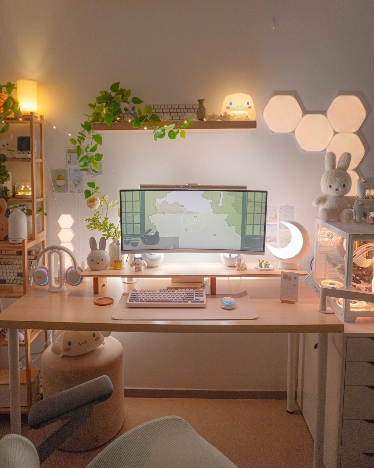 Cozy gaming desk setup with warm lighting, crescent moon lamp, and green plants.