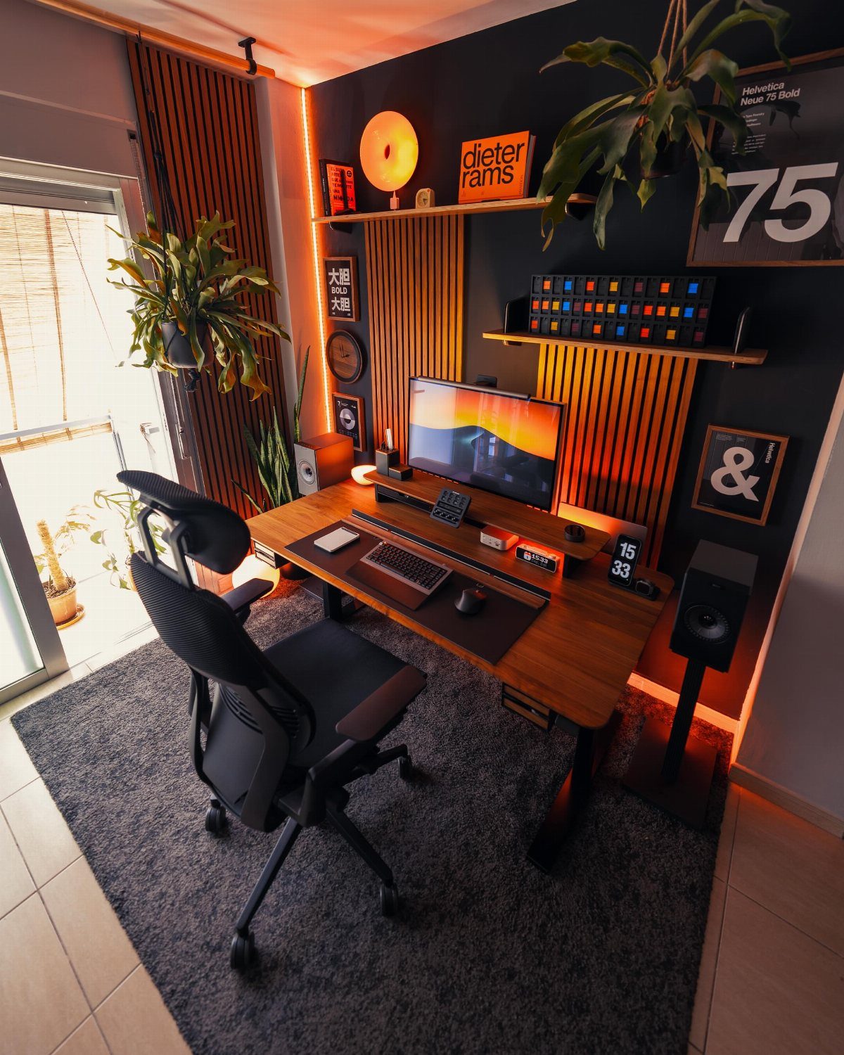 Modern home office nook with wooden desk, ergonomic chair, and orange accent lighting.