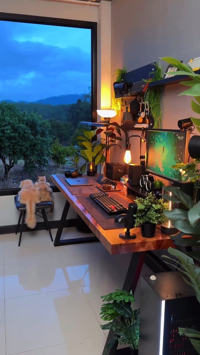 Wooden home office desk positioned next to a window overlooking green mountains.