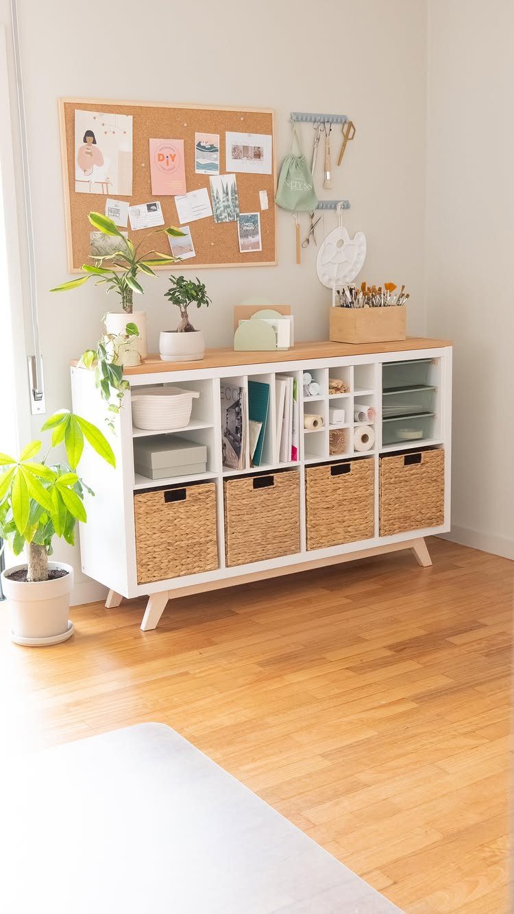 White storage cabinet with woven baskets and a corkboard on a white wall.