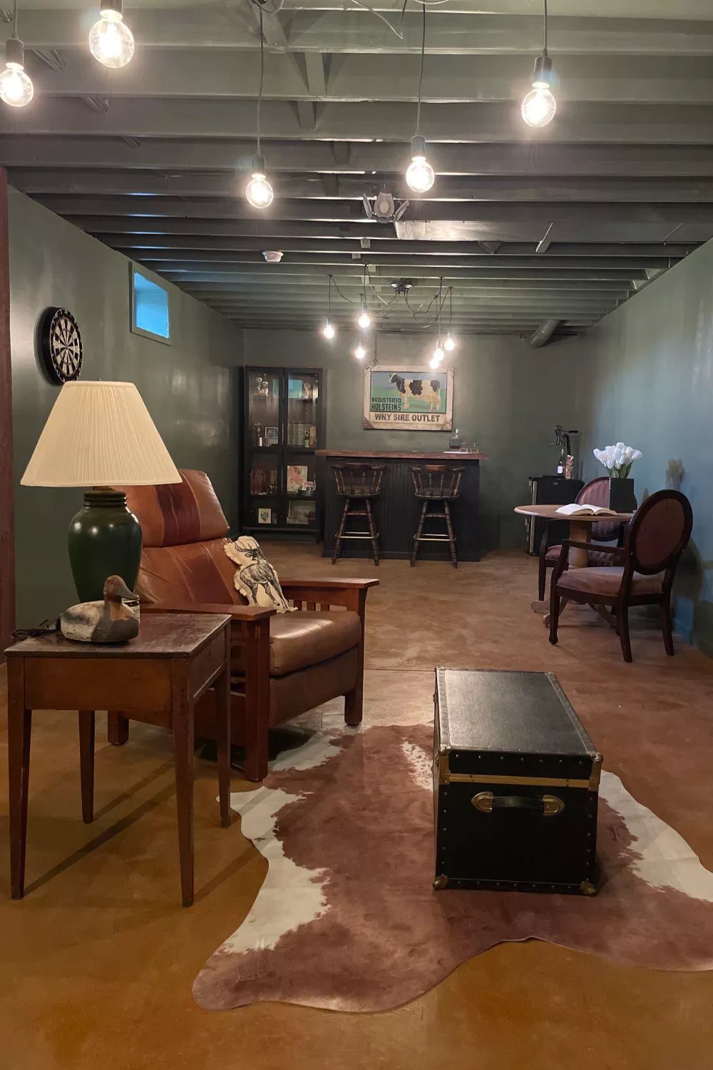 Dark green painted concrete walls in a finished basement with leather furniture.