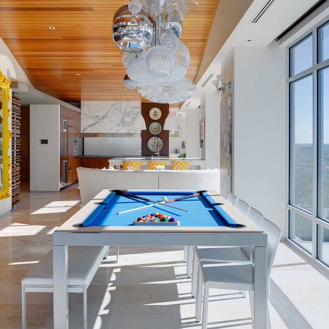 White pool table with blue felt in a modern room with wooden ceilings.