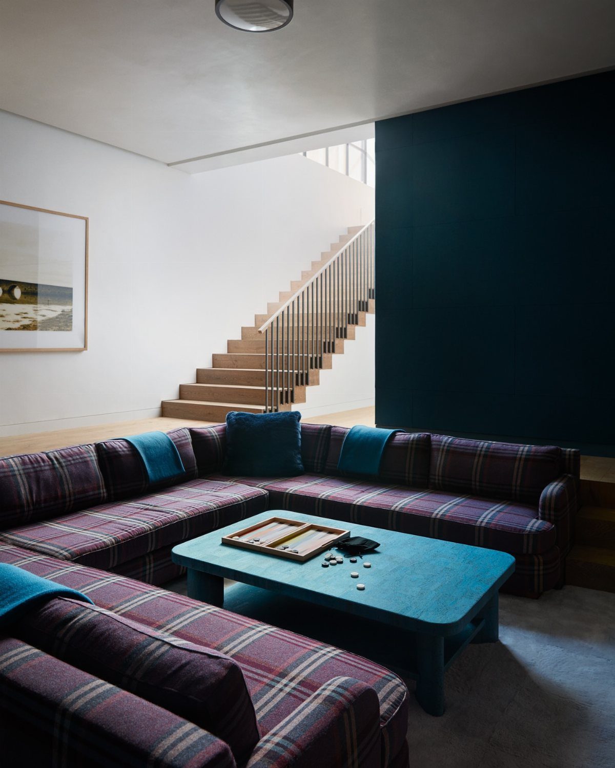 Plaid sectional sofa and blue coffee table in a modern room with teal wall.