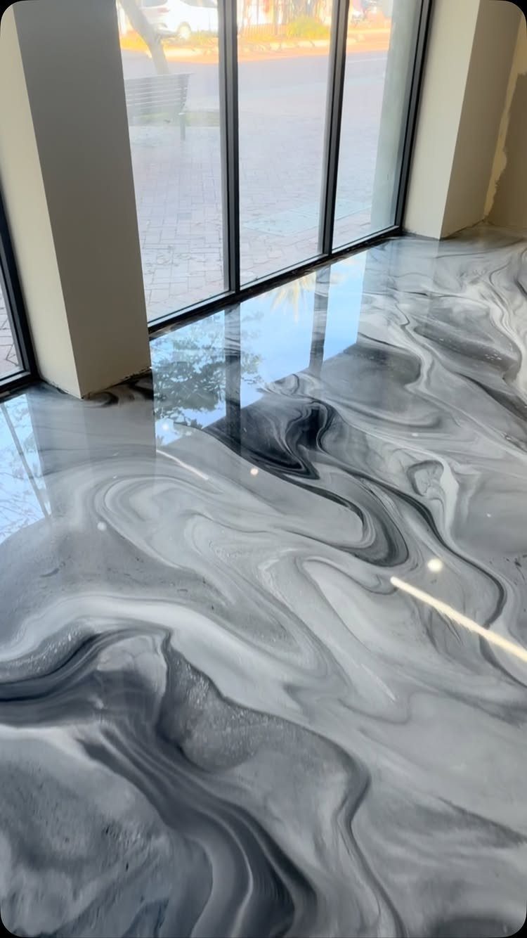 Glossy marbled epoxy floor with grey and white swirls in a bright room