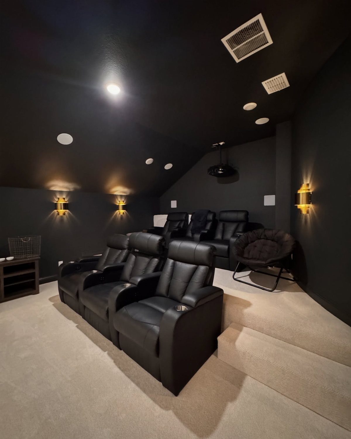 Home cinema room with black leather reclining seats and beige carpeting.