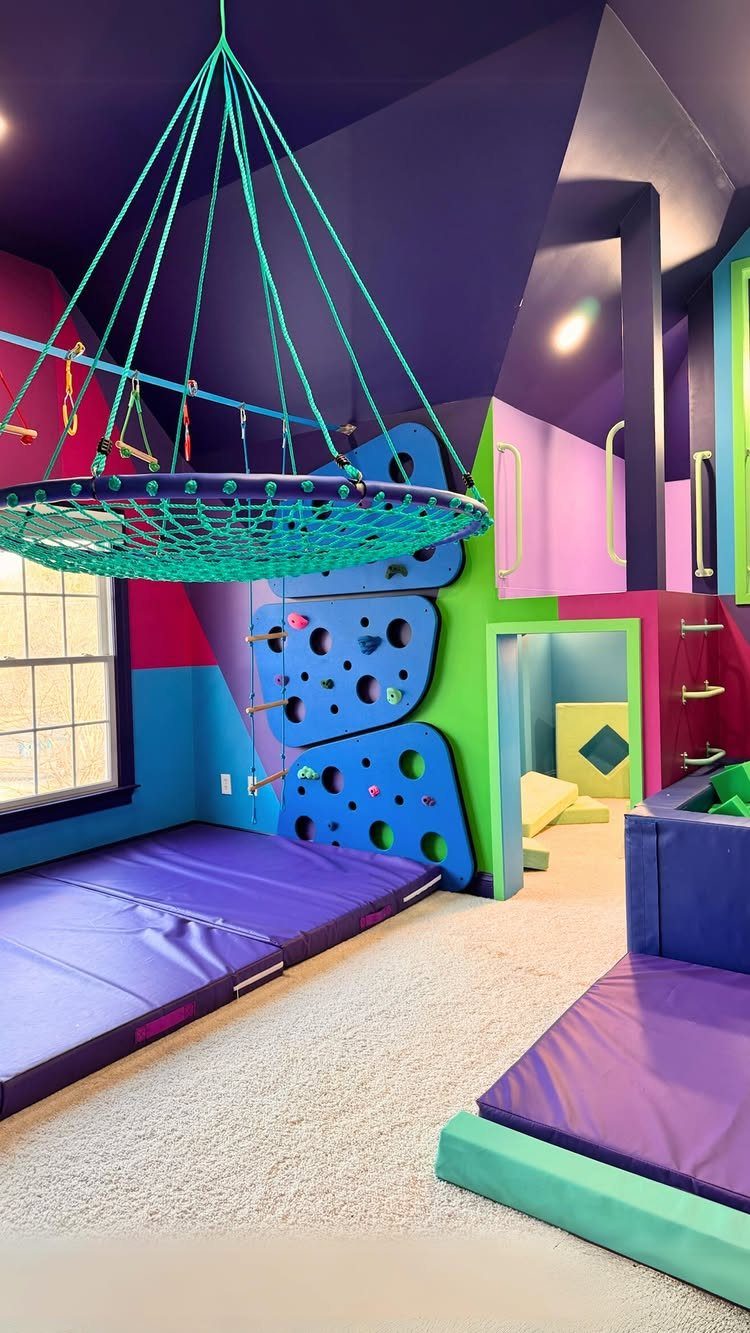Colorful children's recreation room with a climbing wall and hanging rope net.