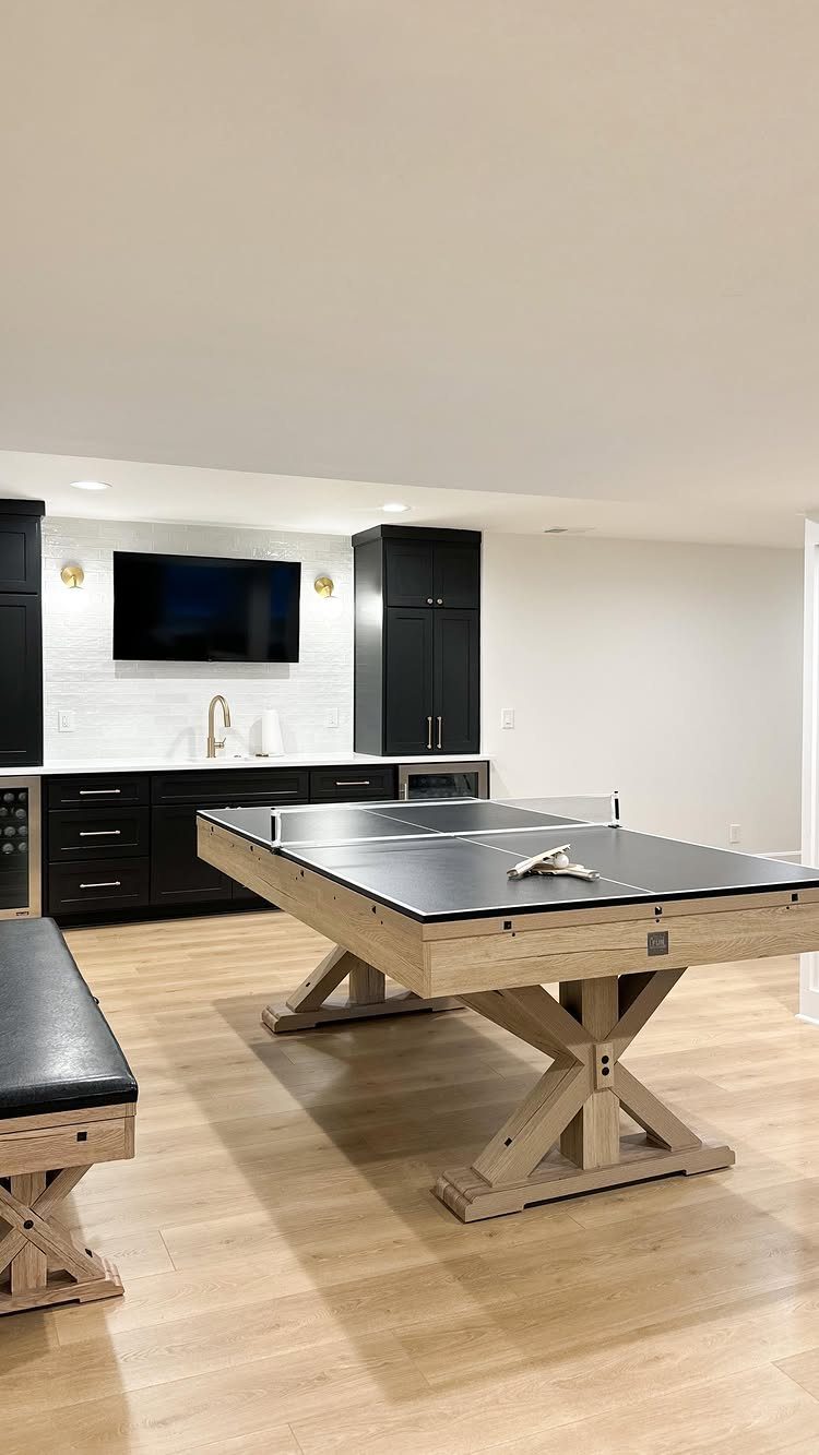 Ping pong table in a modern recreation room with a black wet bar.
