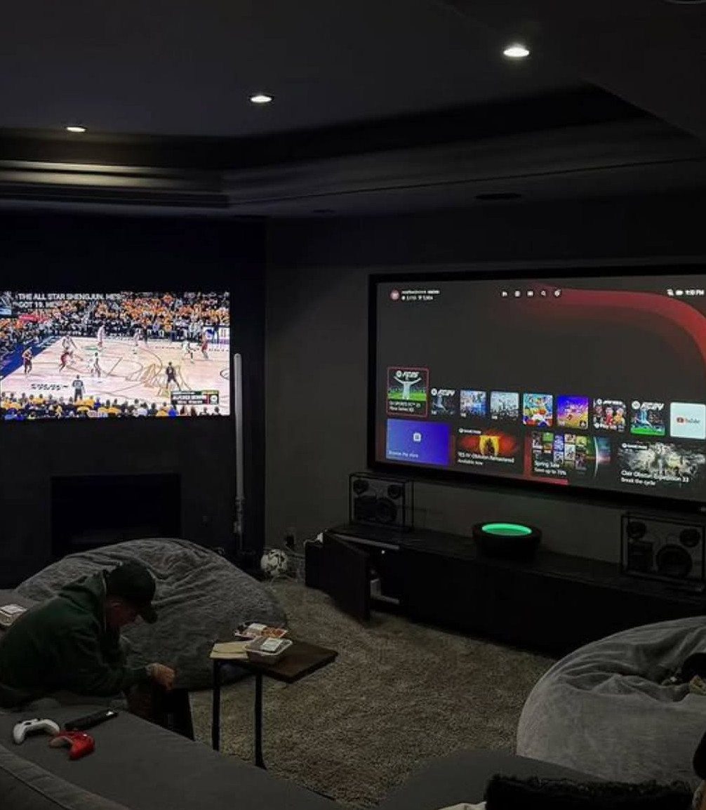Recreation room with large screens, bean bag chairs, and a black media console.