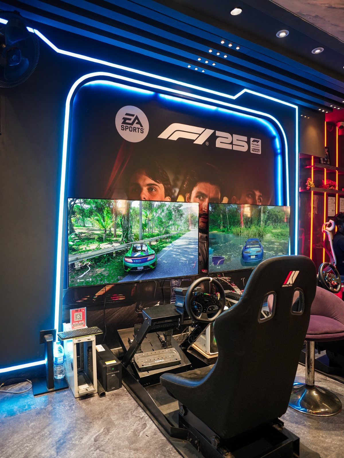 Racing simulator setup with black bucket seat, steering wheel, and dual monitors.