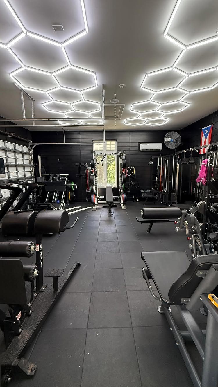 Home gym with weight machines and unique hexagonal LED ceiling lights.