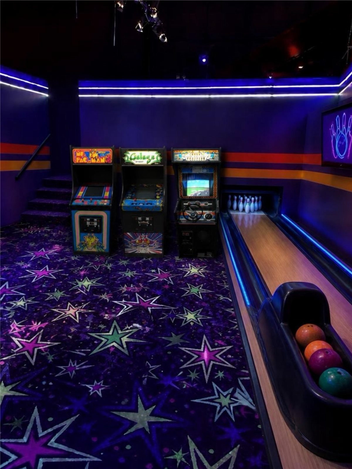 Vintage arcade cabinets and a bowling lane on a purple star-patterned carpet.