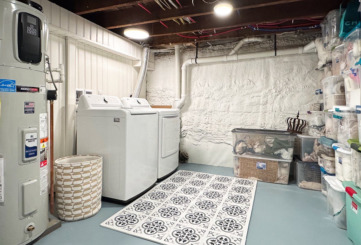 White washing machine and dryer in a basement laundry room with patterned rug.