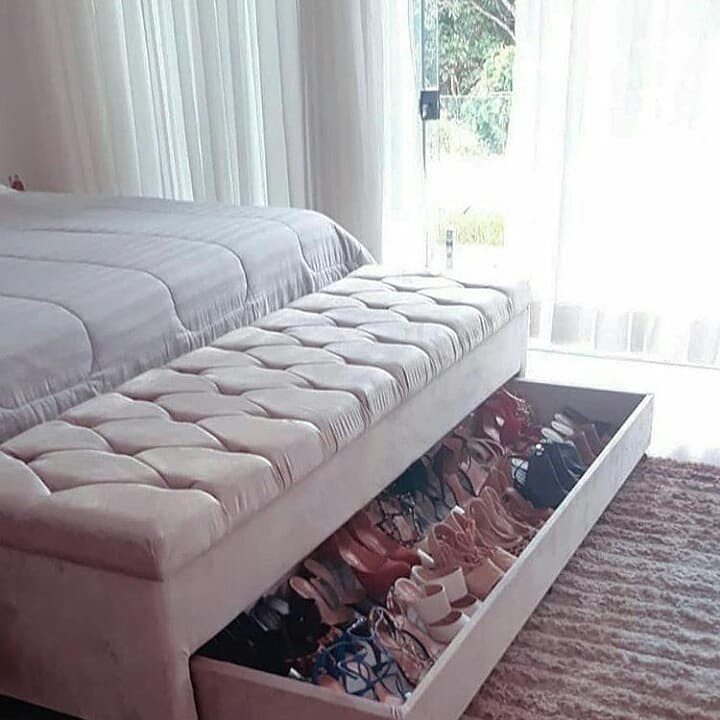 Tufted storage bench at the foot of a bed with open shoe drawer.