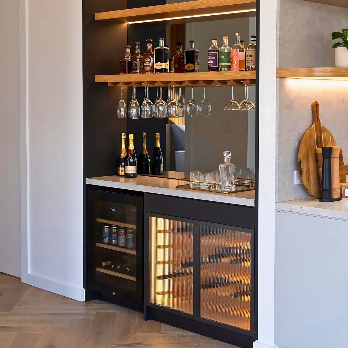 Compact home bar with mirrored back wall, wooden shelves, and integrated wine coolers.