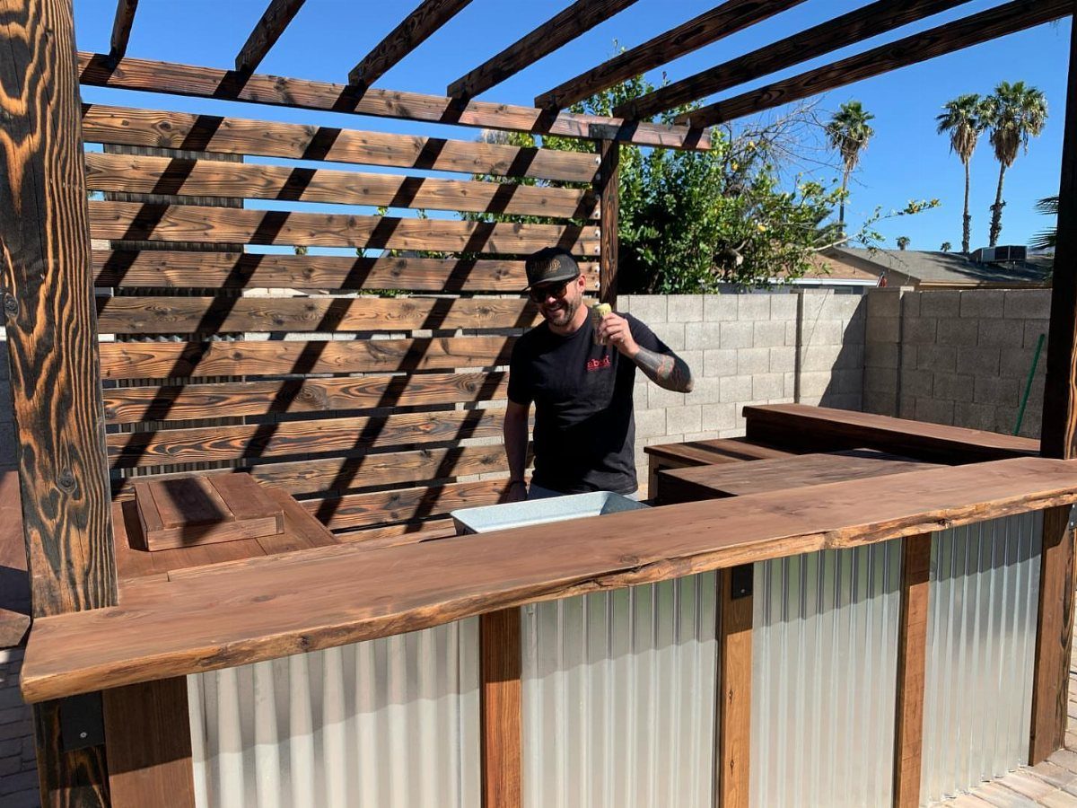 Outdoor home bar with wooden countertop, corrugated metal siding, and built-in ice bucket.