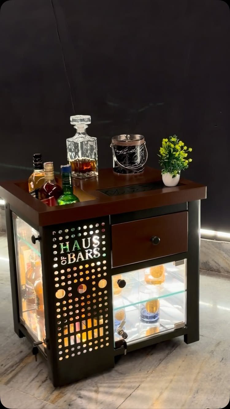 Dark wood mini bar cabinet with illuminated glass shelves and liquor bottles on top