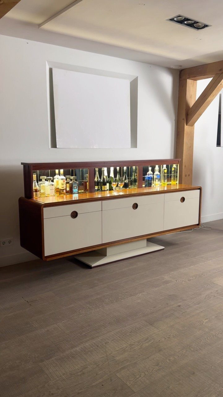 Modern home bar cabinet with white doors and liquor bottles on top shelf