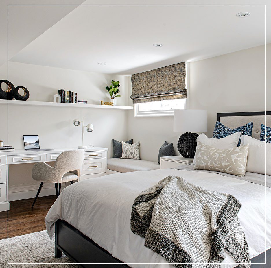 Modern guest bedroom with white bedding, a workspace, and a cozy window seat.