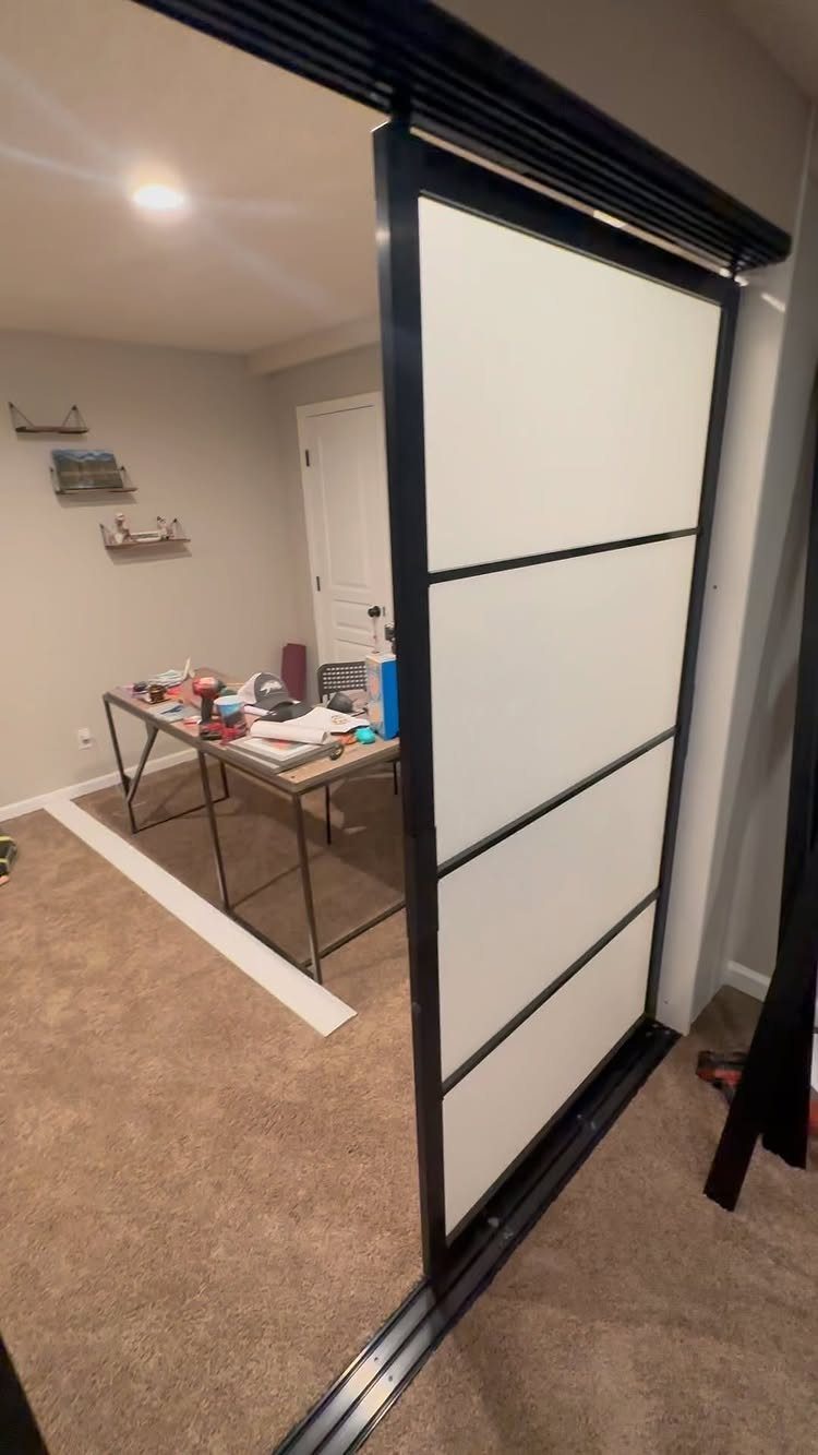 White sliding barn door with black frame opening into a small basement room.