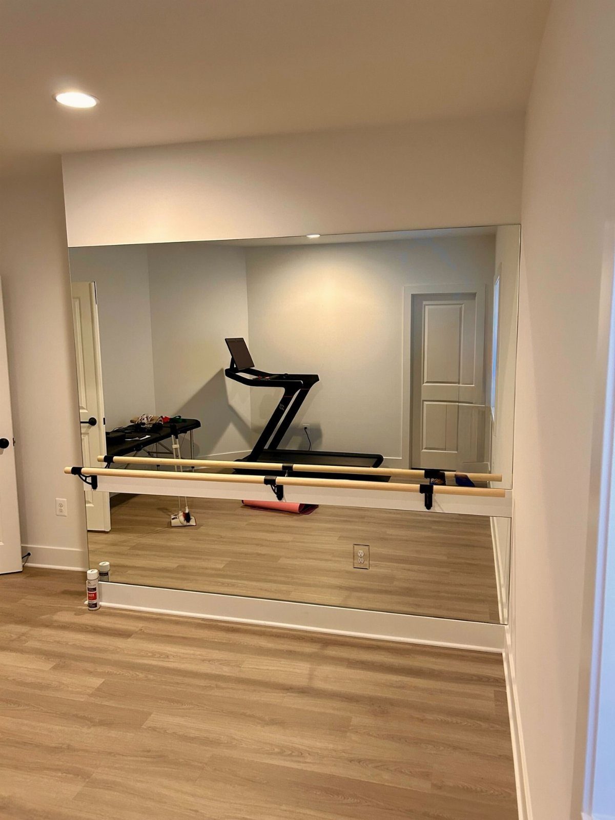Large wall mirror with a wooden ballet barre in a home gym studio