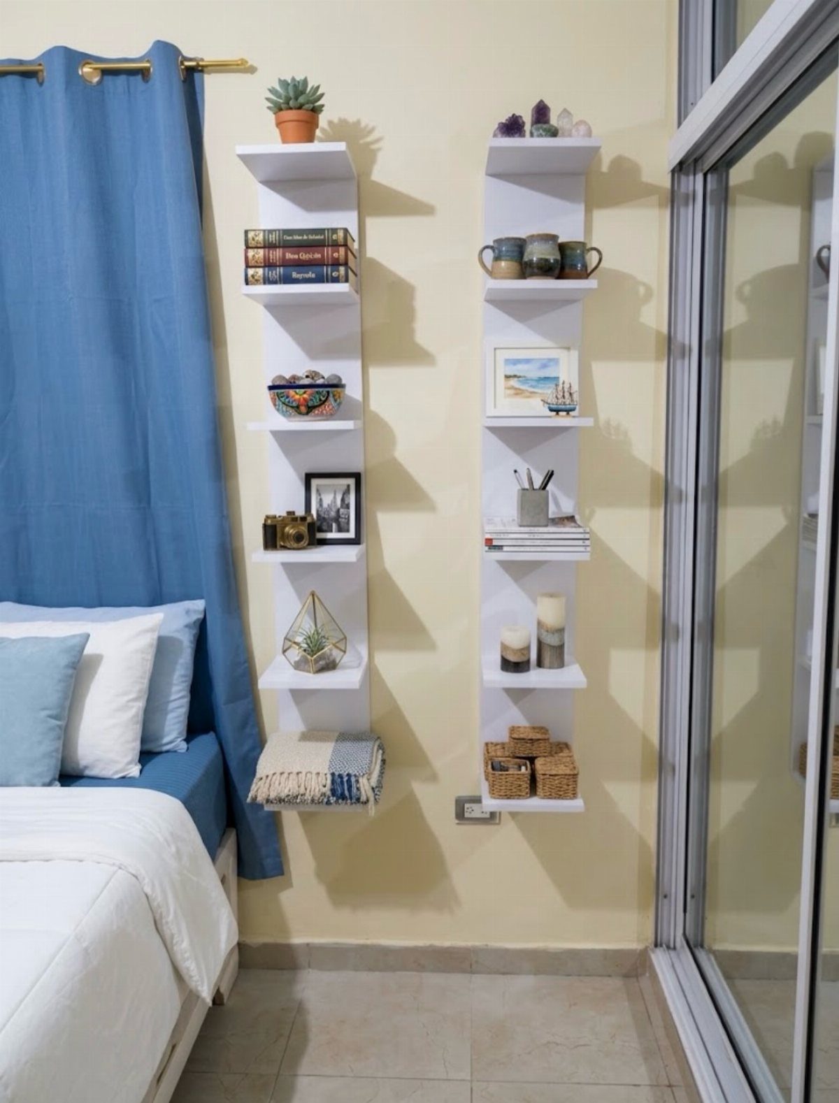 White floating shelves on a yellow wall holding books and decorative bedroom accessories.