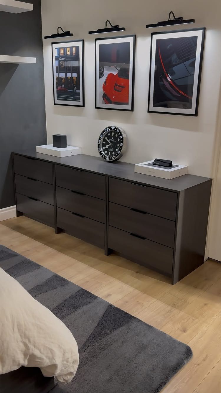 Dark grey dresser with car art and lighting in a small bedroom man cave