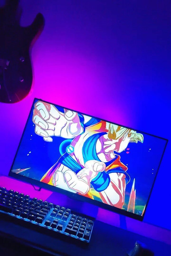 Gaming monitor and keyboard with purple and blue ambient LED wall lighting