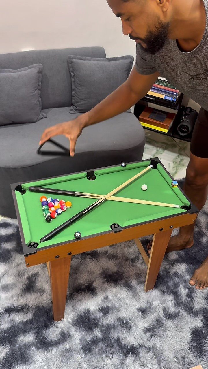 Small wooden pool table with green felt and colorful balls in a living room