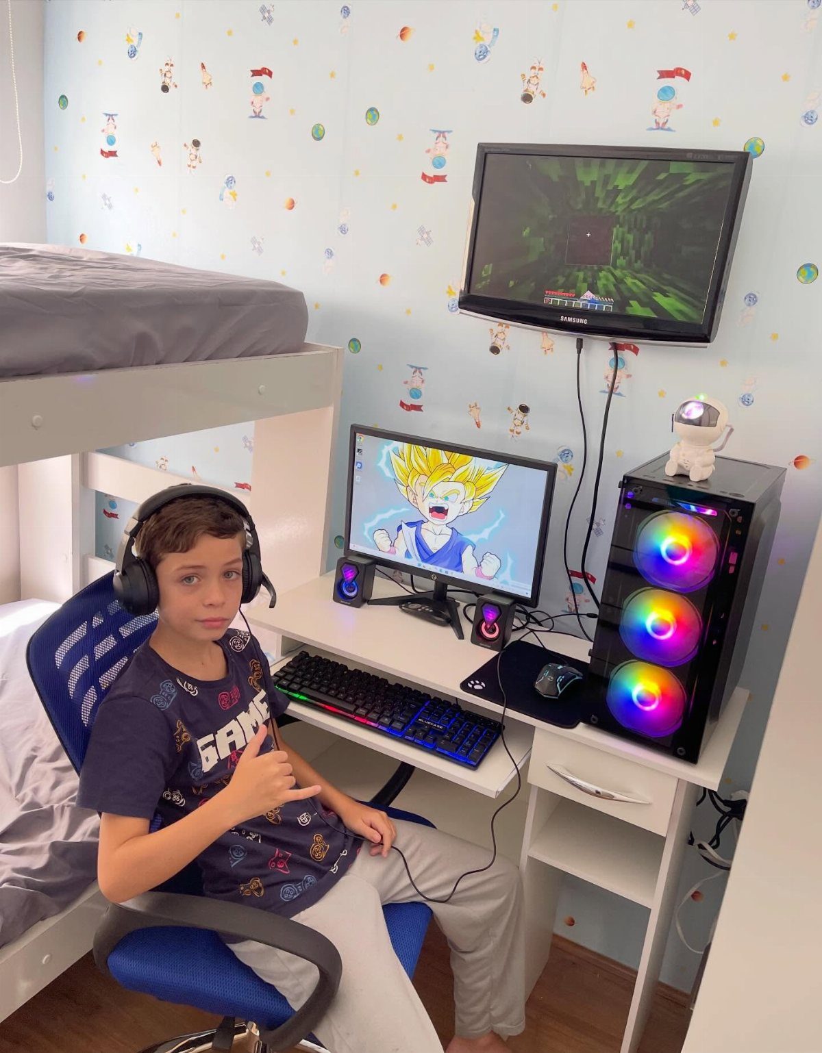 Boy sitting in a gaming chair at a white desk under a loft bed