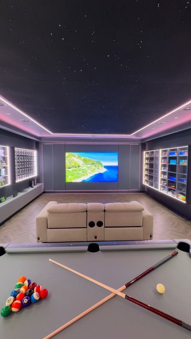 Modern home cinema room with a large screen, beige sofa, and pool table.