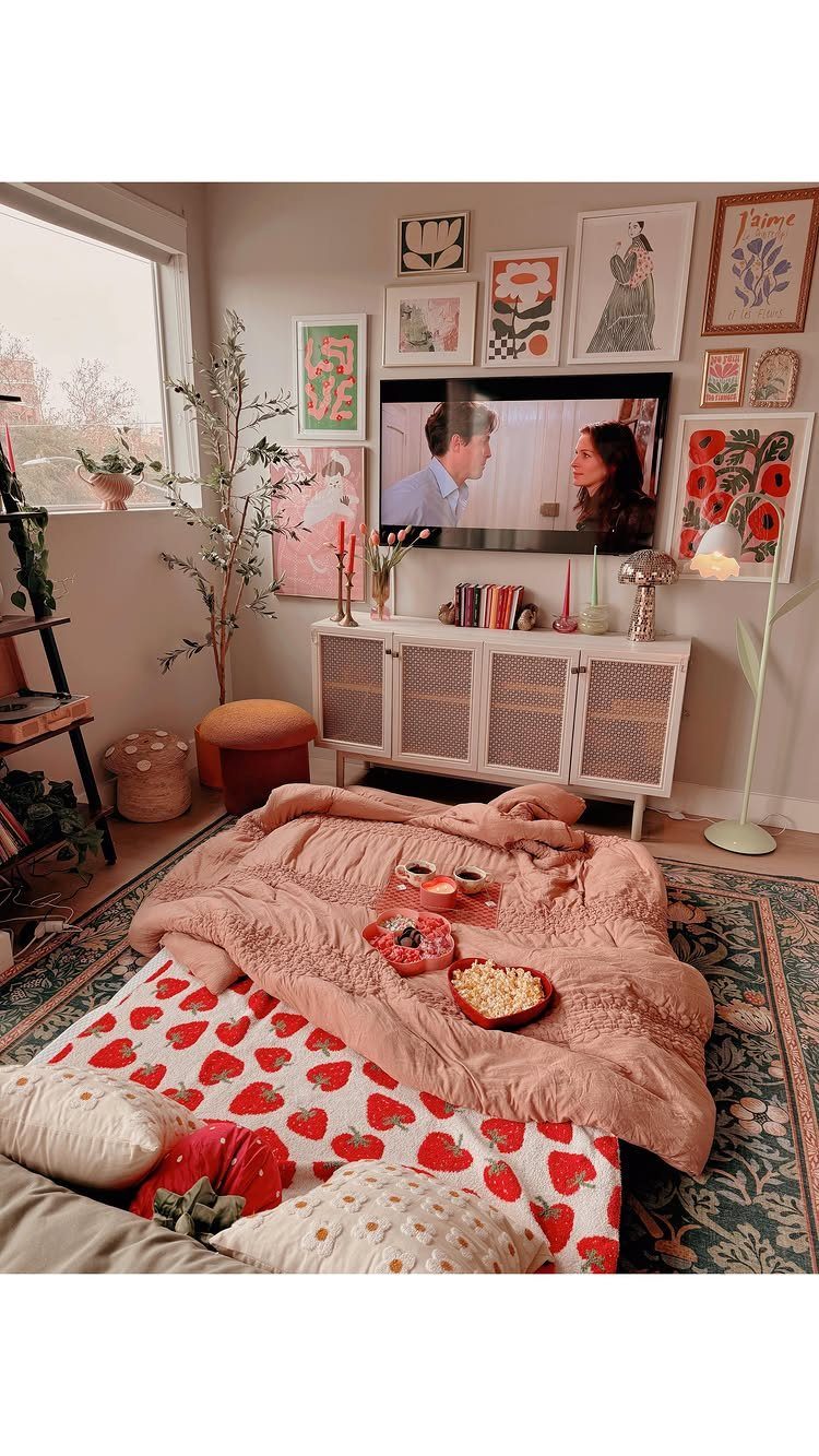 Pink textured blanket and strawberry sheets on a rug in front of a TV