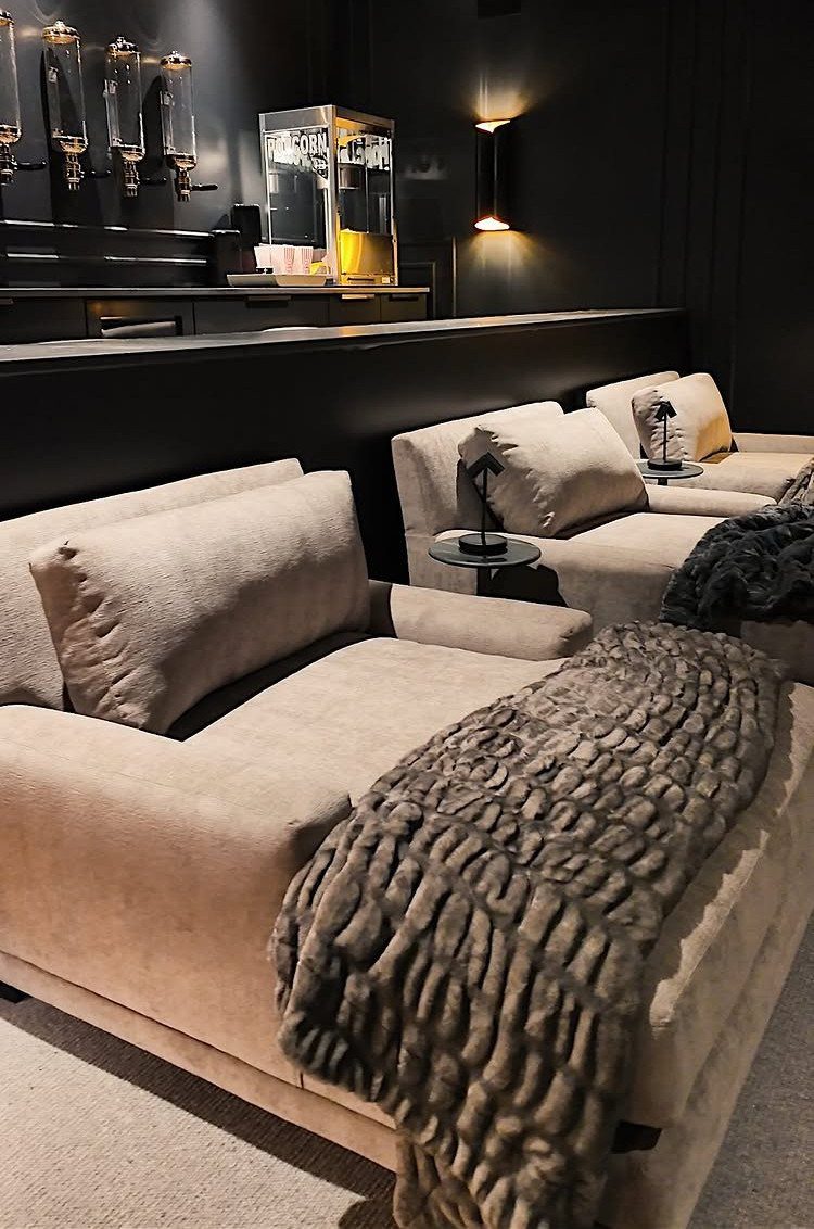 Beige plush lounge seating with pillows and a textured throw in a cinema room