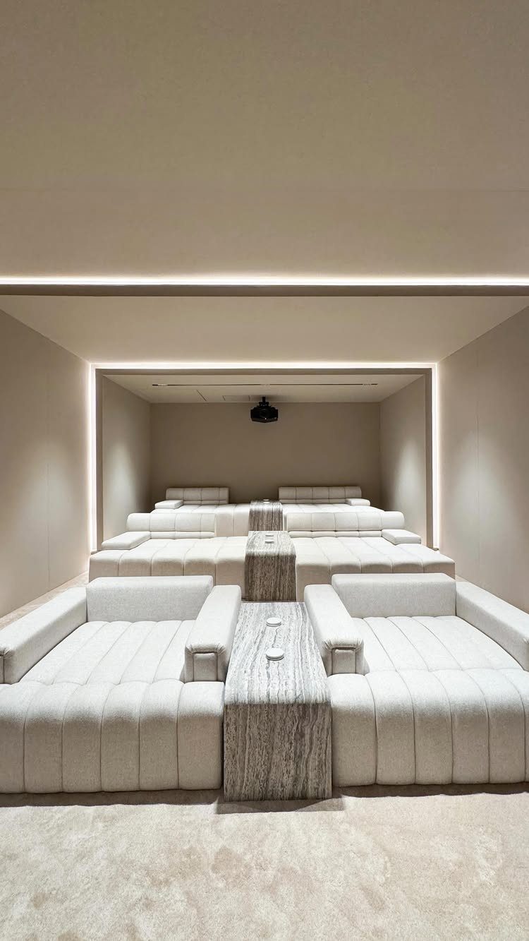 Tiered white upholstered seating and a projector in a modern home cinema room.