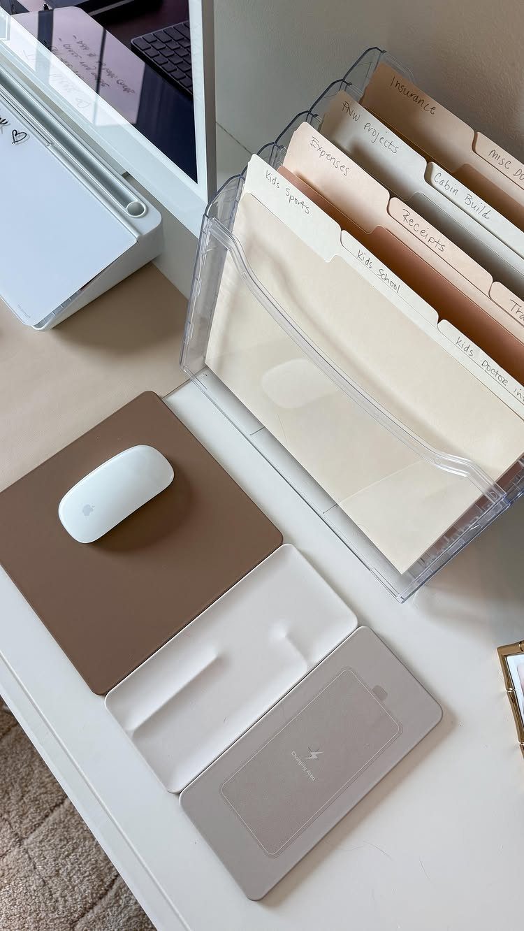 Organized white desk with a mouse, wireless charger, and labeled file folders.