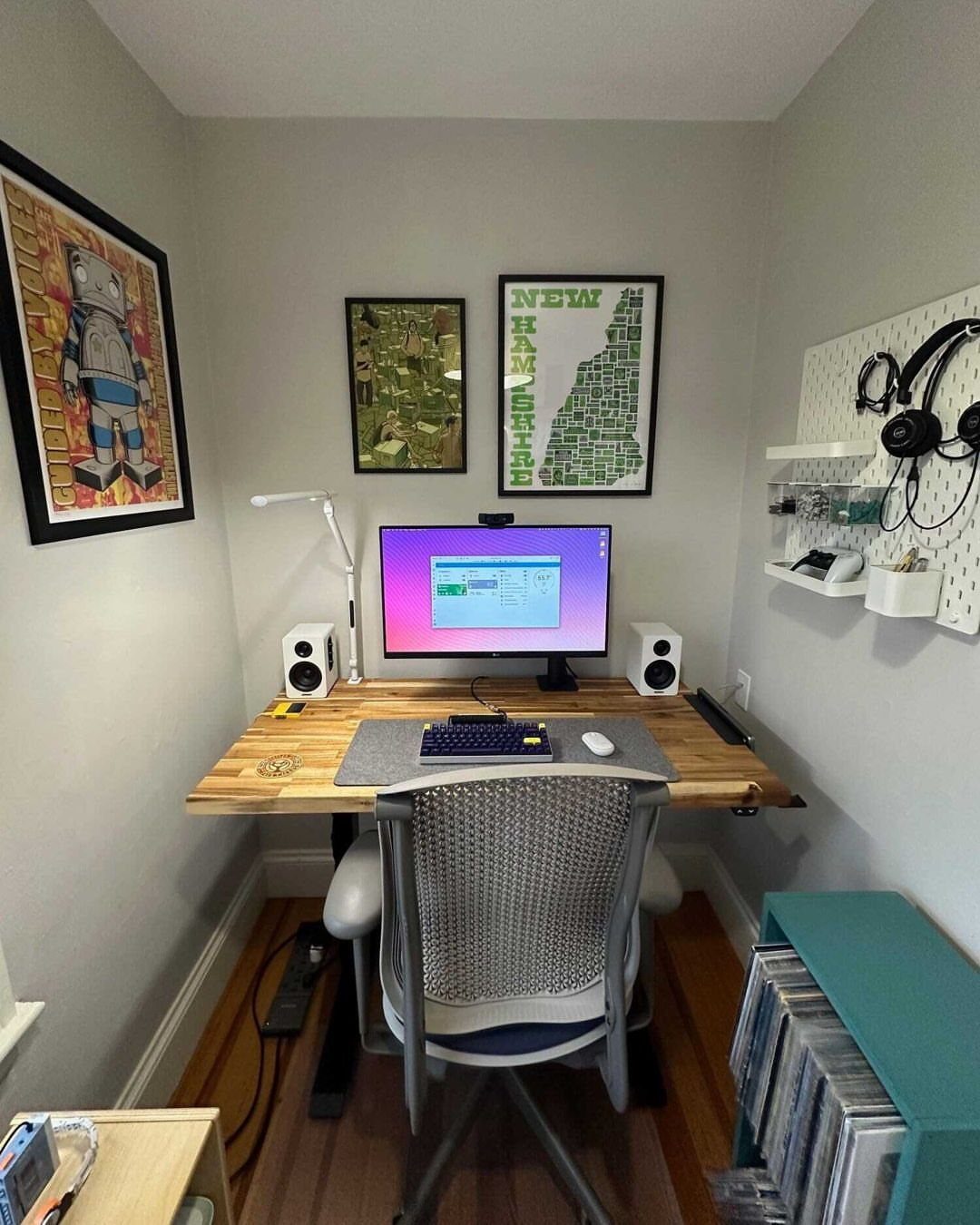 Small home office with a wooden desk and framed art on grey walls.