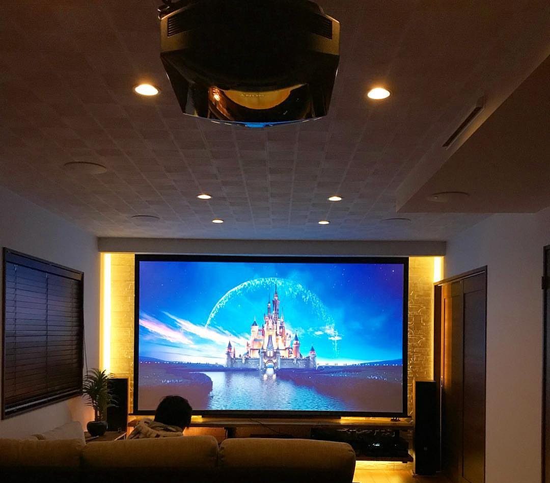 Large projection screen showing a castle in a home theater with ceiling projector.